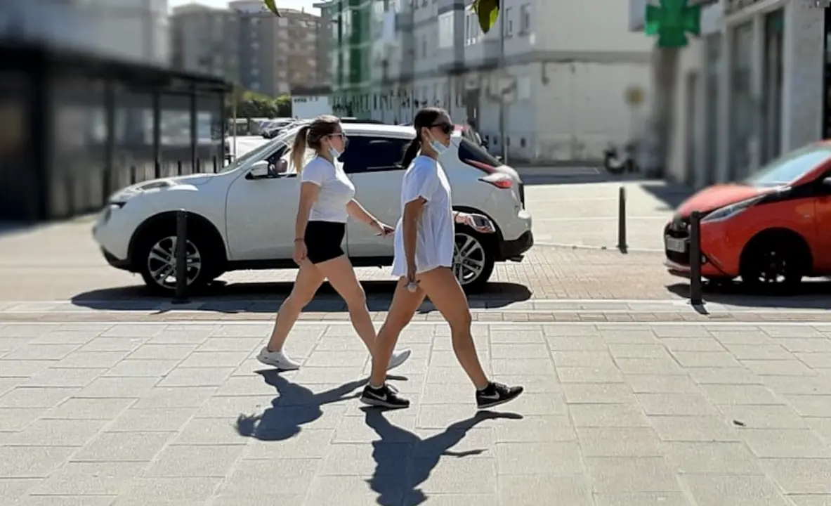 Dos j&oacute;venes caminan con la mascarilla bajada por la Nueva Ciudad de Torrelavega. / S. D&iacute;az