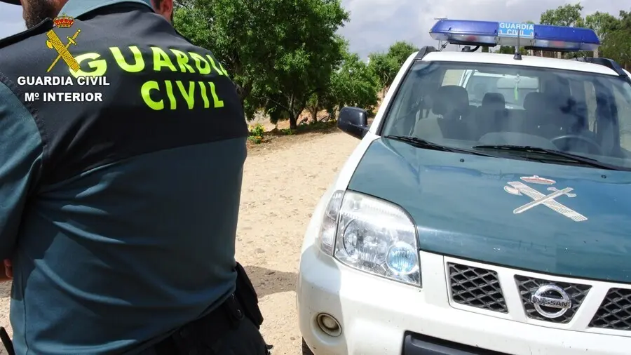 Archivo - Agente de la Guardia Civil junto a su veh&iacute;culo