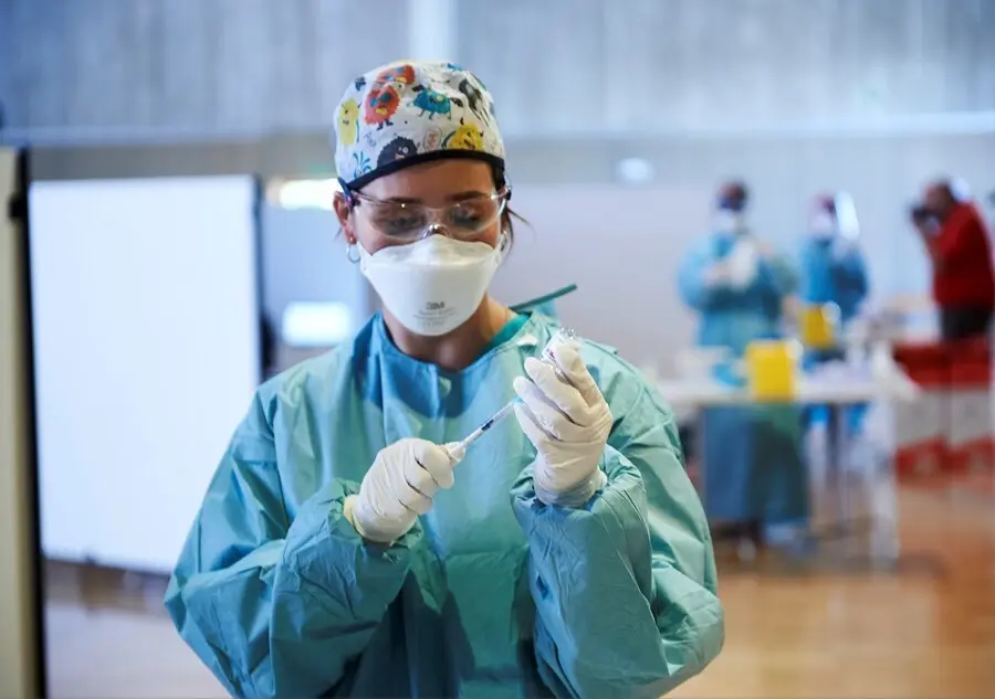 Archivo - Una profesional sanitaria sostiene un vial con la vacuna 