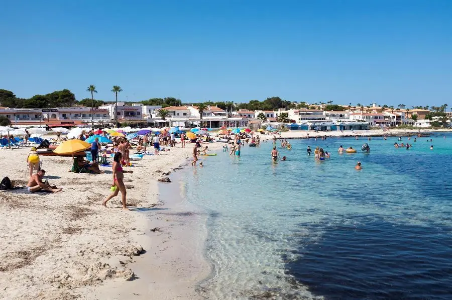 Decenas de personas disfrutan del sol en la playa de Punta Prima (Menorca), este mi&eacute;rcoles. La Agencia Estatal de Meteorolog&iacute;a (Aemet) prev&eacute; para ma&ntilde;ana, jueves, temperaturas significativamente altas en buena parte del interior peninsular y Baleares, as&iacute; como intervalos de viento fuerte en Canarias. EFE/David Arquimbau Sintes