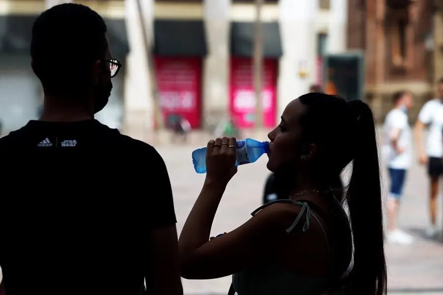 Varias personas intentan protegerse del calor en el d&iacute;a donde la capital andaluza se encuentra  en  aviso naranja por temperaturas que superar&aacute;n los 40 grados en algunos puntos de la capital y la provincia a 12 de julio del 2021 en M&aacute;laga (Andaluc&iacute;a). 