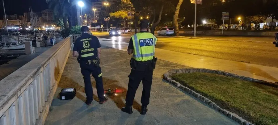 Un agente de la Polic&iacute;a Local y un agente de la direcci&oacute;n General de Emergencias del Govern junto al dron utilizado en el dispositivo antibotell&oacute;n.