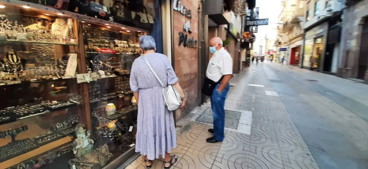 Dos personas miran un escaparate en la calle Consolaci&oacute;n de Torrelavega. / HARDY