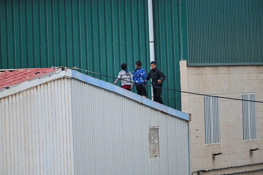 Archivo - Varios ni&ntilde;os caminan por un tejado de la nave de primera acogida del pol&iacute;gono del Tarajal, en Ceuta.