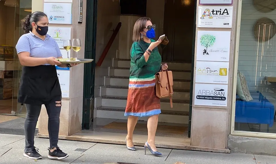 Una camarera y una otra persona que sale de un edificio de oficinas en Santander. / Hardy