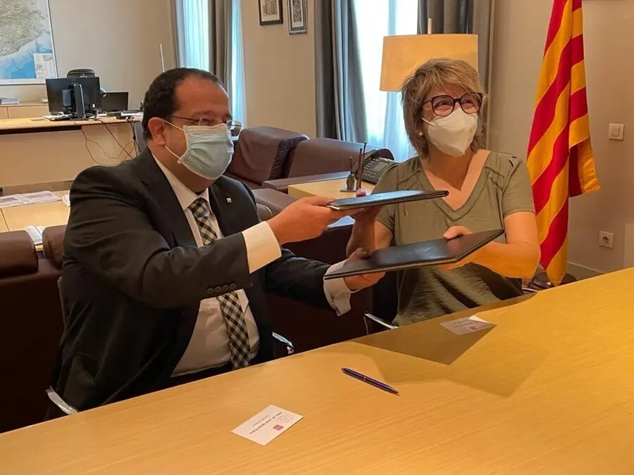 El conseller de Interior de la Generalitat, Joan Ignasi Elena, y la vicepresidenta primera de la Fundaci&oacute;n APIP-ACAM, Montserrat Font, firman un convenio de colaboraci&oacute;n contra el tr&aacute;fico de seres humanos. Barcelona, 30 de julio de 2021.