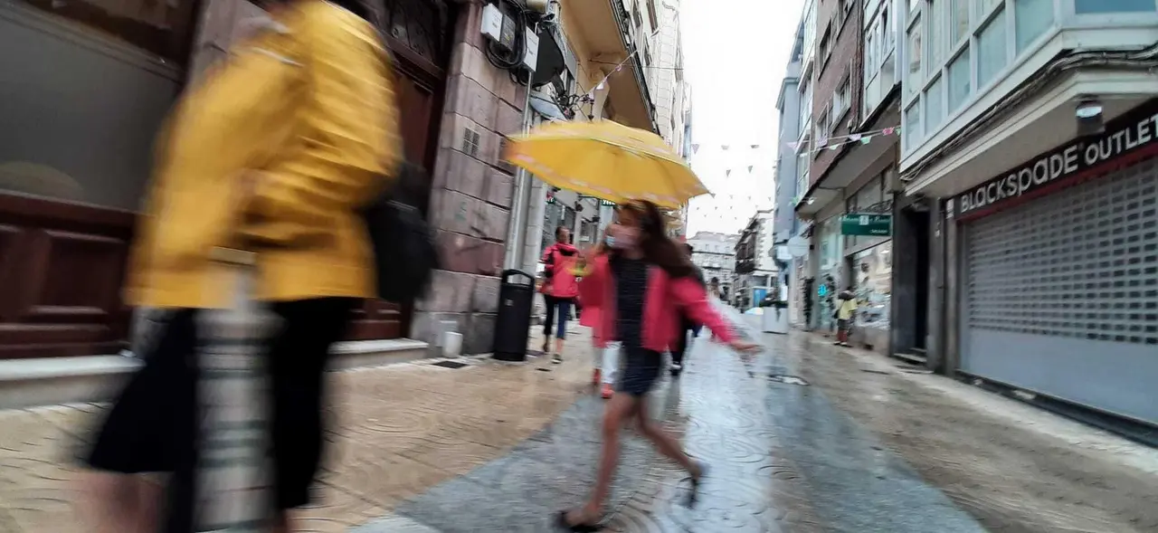 Una ni&ntilde;a con mascarilla y paraguas por las calles de Torrelavega. / S. D&iacute;az