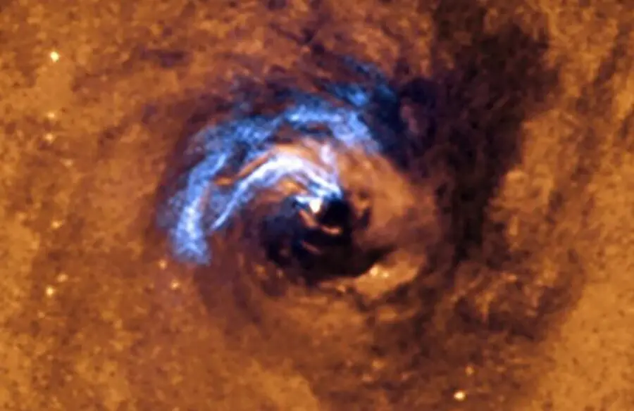 La imagen muestra el proceso de alimentaci&oacute;n nuclear de un agujero negro en la galaxia NGC 1566, y c&oacute;mo los filamentos de polvo, que rodean al n&uacute;cleo activo, quedan atrapados y giran en espiral alrededor del agujero negro hasta que se los traga.