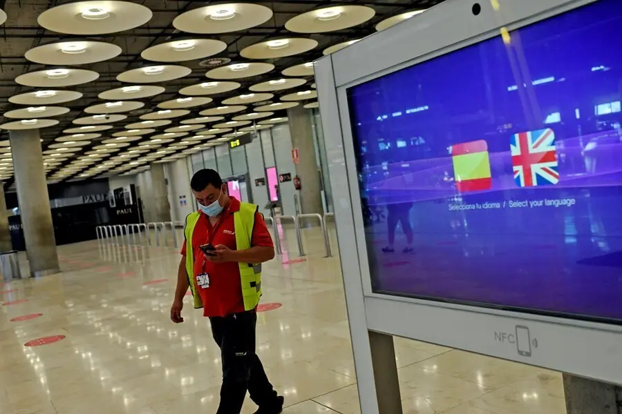 Archivo - Un operario de Iberia pasa al lado de un monitor con las banderas de Espa&ntilde;a y Reino Unido en la T1 del Aeropuerto de Madrid-Barajas Adolfo Su&aacute;rez, en Madrid (Espa&ntilde;a), a 27 de julio de 2020. 