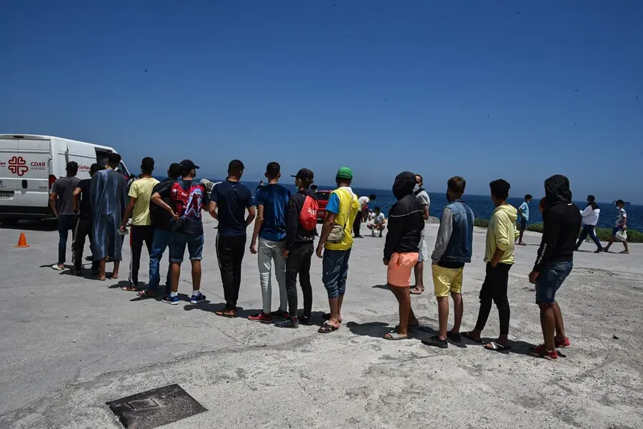 Archivo - Varios migrantes que entraron a Ceuta hacen cola para recibir alimentos de C&aacute;ritas Diocesana.
