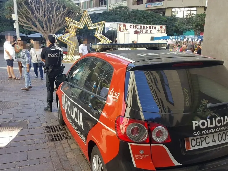 Archivo - Agente de la Polic&iacute;a Canaria junto a un coche patrulla