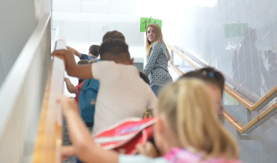 Archivo - Ni&ntilde;os de Primaria se dirigen a su aula junto a una trabajadora del centro escolar