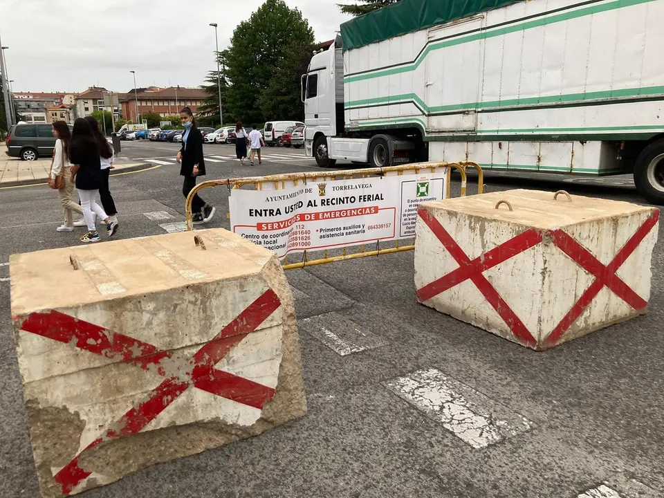 Varias personas pasan delante de un cartel que divide la zona de las atracciones en Torrelavega. / S. D&iacute;az