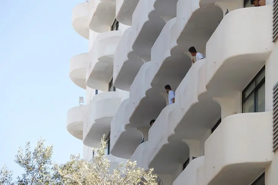 Archivo - Dos j&oacute;venes en un balc&oacute;n del hotel Palma Bellver, donde estaban confinados los estudiantes del 'macrobrote'.