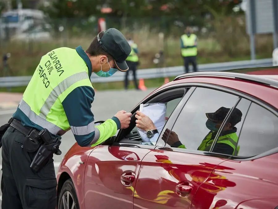 Archivo - Un agente de la Guardia Civil de Tr&aacute;fico comprueba la documentaci&oacute;n de un conductor en un control policial, en una imagen de archivo.