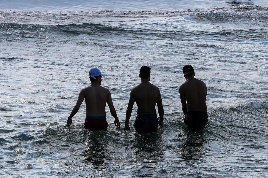 Archivo - Varias personas toman un ba&ntilde;o en la playa