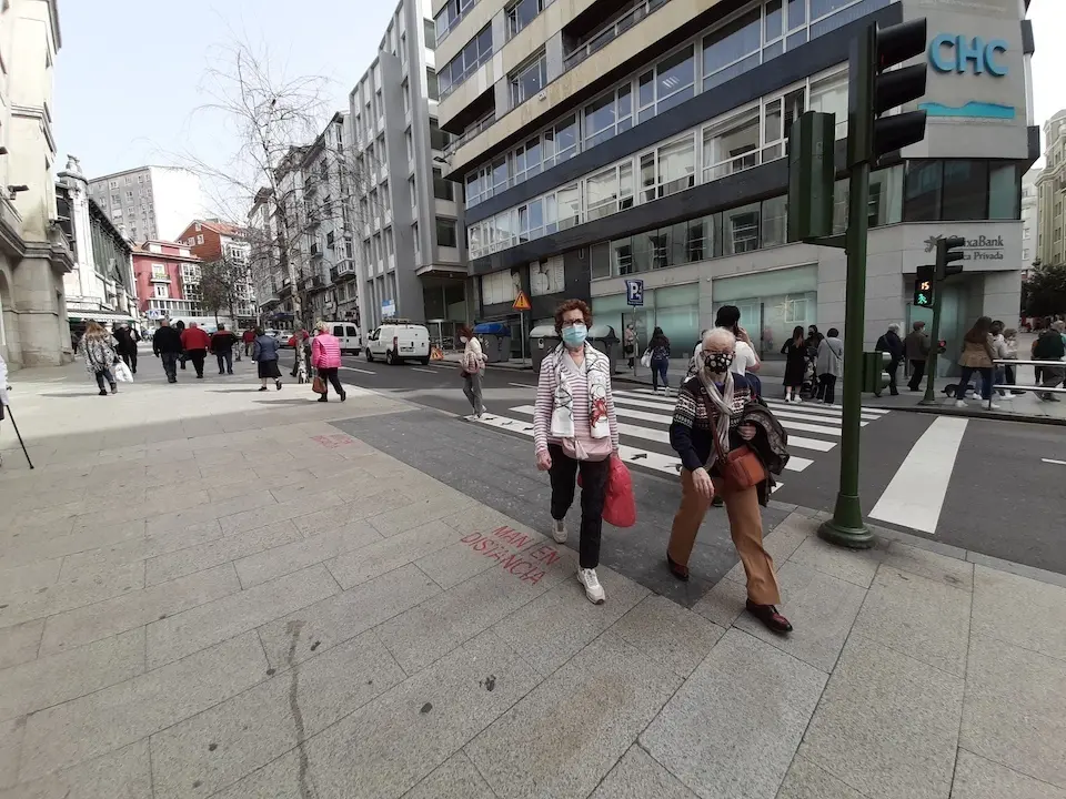 Varias personas con mascarilla cruzan una calle junto al Ayuntamiento de Santander. / S. D&iacute;az
