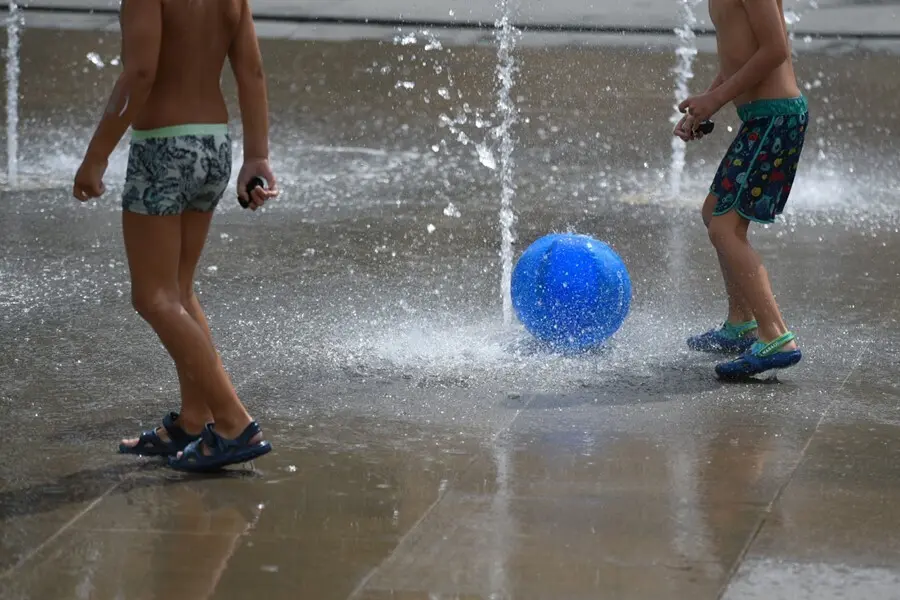 Dos ni&ntilde;os juegan en una fuente del Parc Central, a 12 de agosto de 2021, en Valencia, Comunidad Valenciana (Espa&ntilde;a)