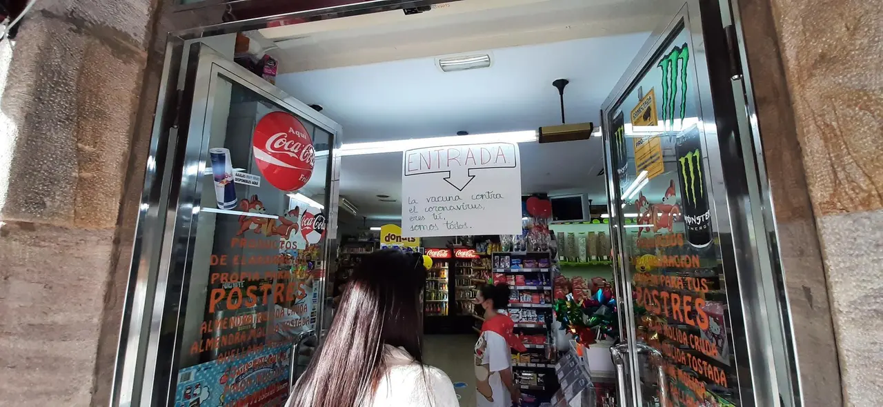 Varias personas esperan su turno para entrar en una tienda de comestibles de Torrelavega. / S. D&iacute;az