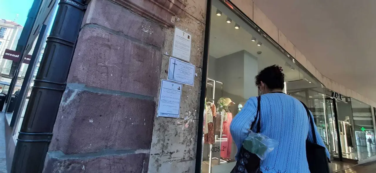 Una persona ojea las esquelas puestas en la pared al lado de la tienda Zara de Torrelavega. / S. D&iacute;az