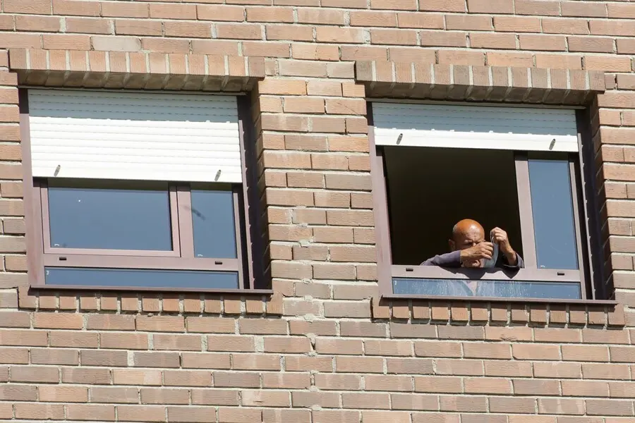 Un anciano coloca su mascarilla en la ventana de su habitaci&oacute;n de la residencia de mayores