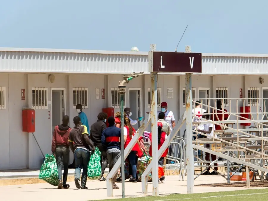 Archivo - Varios migrantes acceden junto a miembros de la Cruz Roja a las instalaciones de la Ciudad del F&uacute;tbol del Altos del Real a 18 de mayo de 2021, en Melilla (Espa&ntilde;a). 
