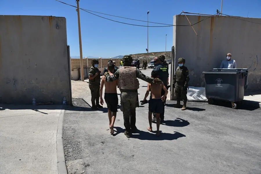 Archivo - Un militar del ej&eacute;rcito espa&ntilde;ol y un agente de la Guardia Civil ayudan a dos menores migrantes procedentes de Marruecos