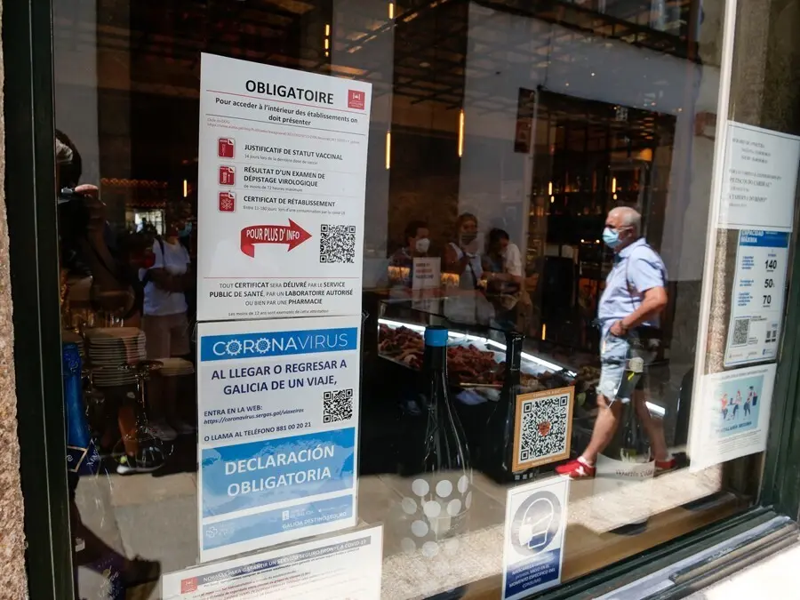 Carteles en diferentes idiomas de indicaciones de obligatoriedad de presentar certificados antes de acceder al interior, a 12 de agosto de 2021, en Santiago de Compostela, A Coru&ntilde;a, Galicia (Espa&ntilde;a).