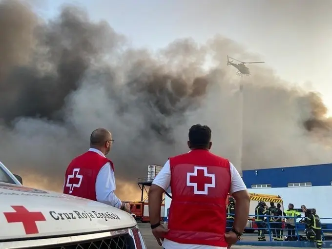 Voluntarios de Cruz Roja contemplan la columna de humo en la central hostofrut&iacute;cola de El Escobar.