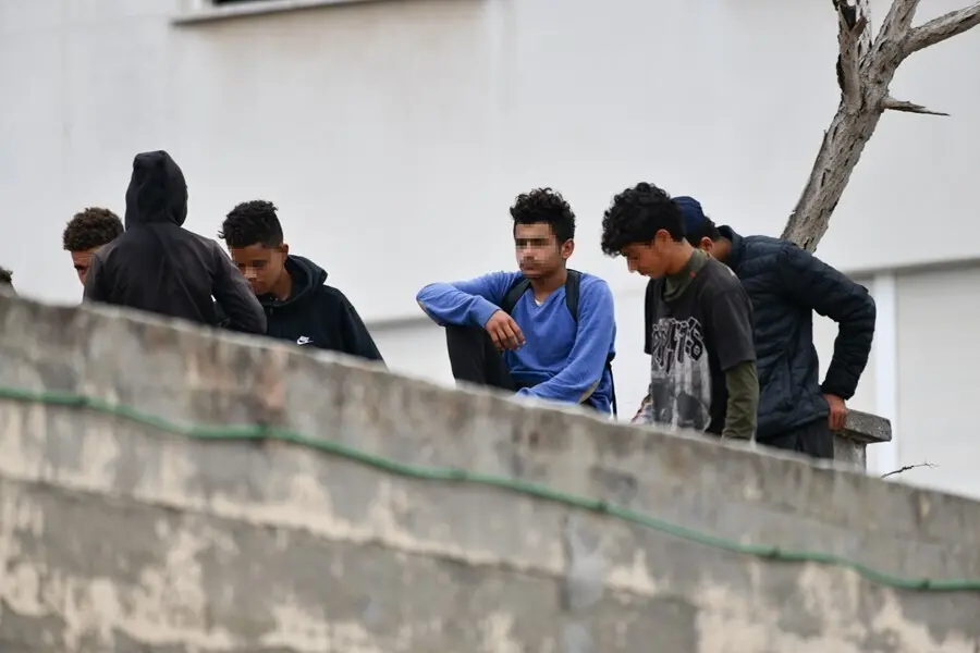 Varios menores migrantes, en el tejado de una nave industrial, a 27 de agosto de 2021, en Ceuta, (Espa&ntilde;a). La Polic&iacute;a Nacional ha desalojado a varios menores que se encontraban en el tejado de esta vieja nave industrial, en la zona portuaria de Ceuta.