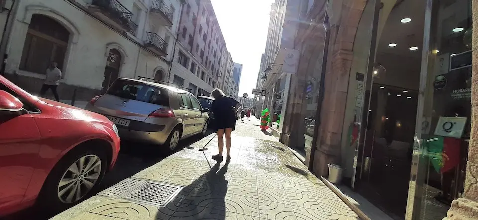 Una persona limpia la acera frente al comercio donde trabaja. / S. D&iacute;az