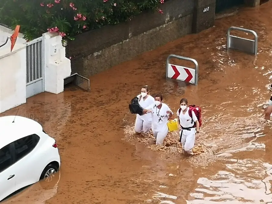 Tres sanitarias atraviesan una calle inundada este domingo en Benic&agrave;ssim (Castell&oacute;n)