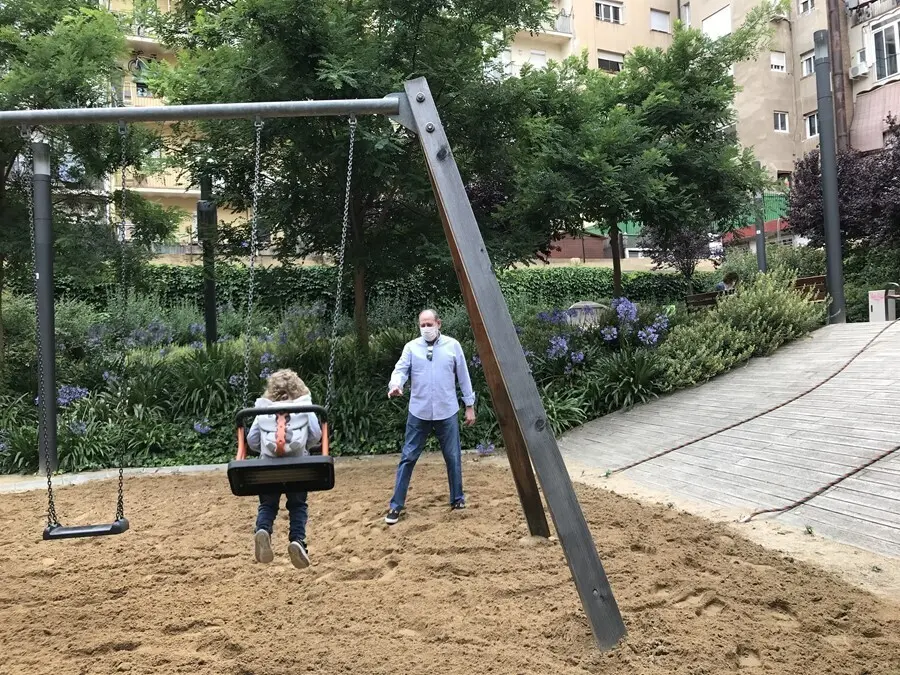 Archivo - Una ni&ntilde;a y su abuelo juegan en los columpios.