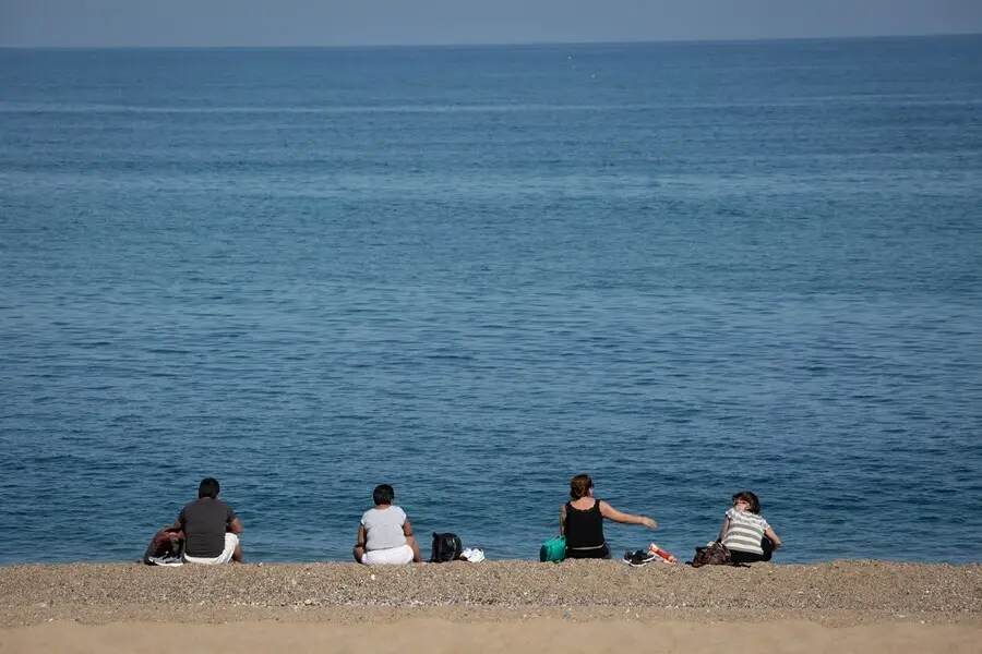 Archivo - Varias personas sentadas en la Playa de la Barceloneta de Barcelona