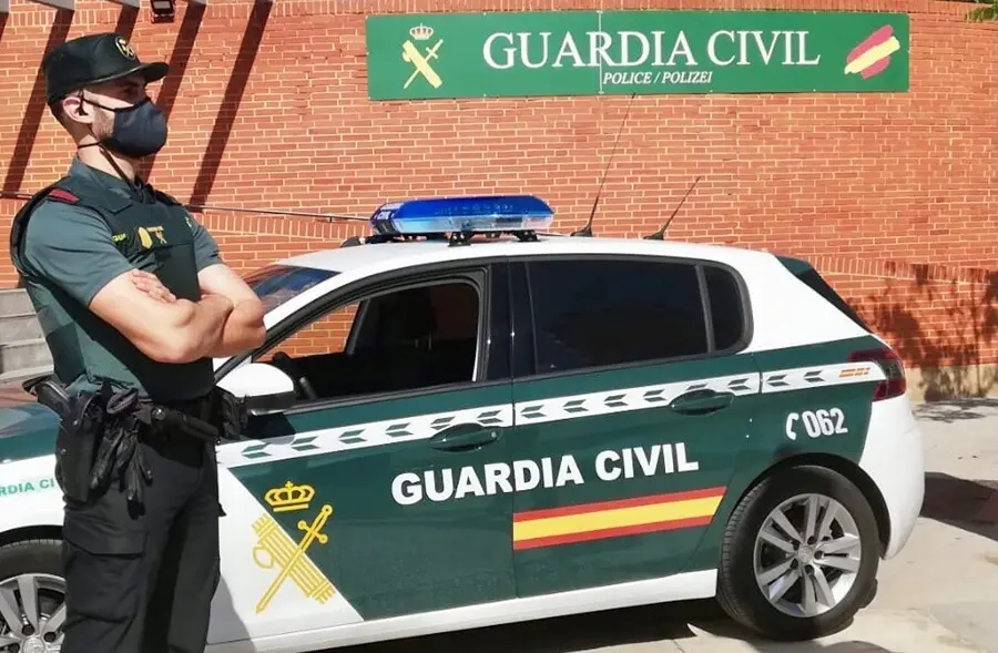 Archivo - Un agente de la Guardia Civil, junto a un veh&iacute;culo del cuerpo.