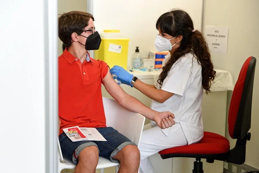 Una sanitaria vacuna a un adolescente con la primera dosis de la vacuna Moderna 