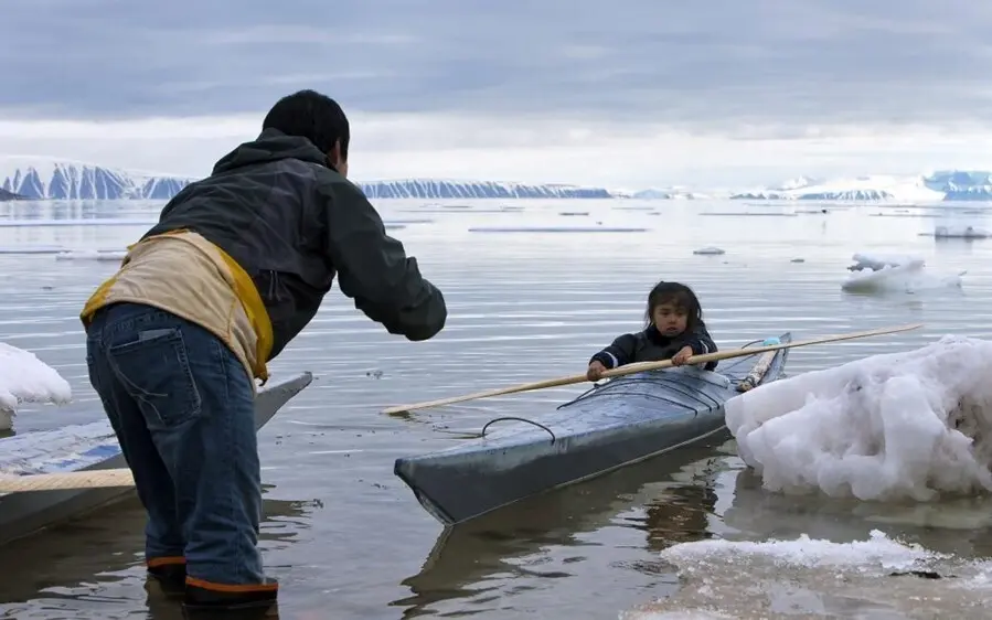 En la foto, un adulto ense&ntilde;a a un ni&ntilde;o a remar cerca de Siorapaluk en el noroeste de Groenlandia.
