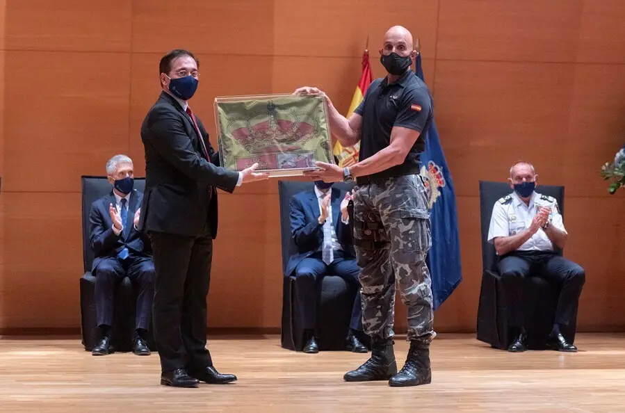 Un polic&iacute;a del Grupo Especial de Operaciones (GEO) entrega al ministro de Asuntos Exteriores, Jos&eacute; Manuel Albares, la bandera nacional que ondeaba en la Embajada de Kabul