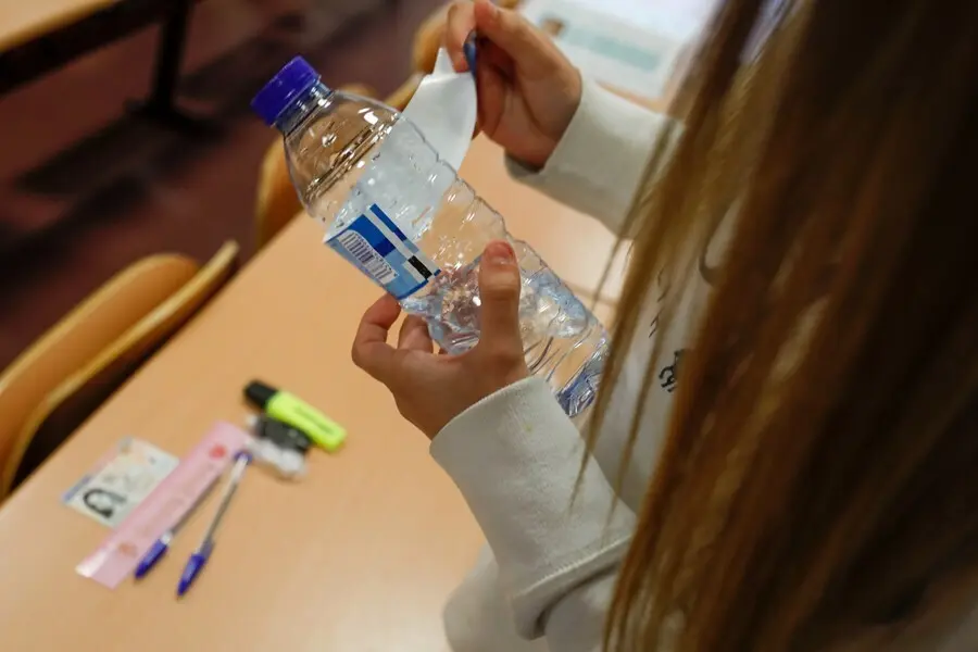 Archivo - Una joven despega el papel de la botella cumpliendo las normas a seguir para la convocatoria extraordinaria de la Evaluaci&oacute;n del Bachillerato para el Acceso a la Universidad (EBAU), a 6 de julio de 2021, en Madrid