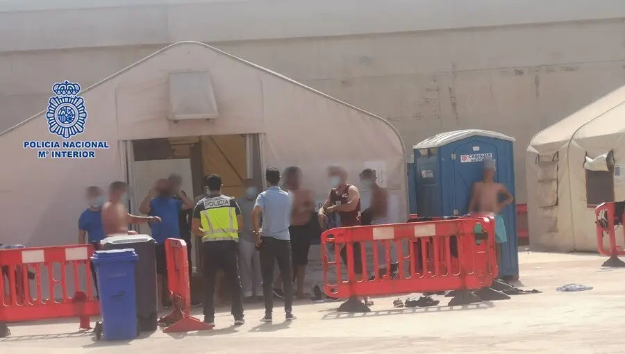Personas en situaci&oacute;n irregular llegadas a la costa murciana en pateras esperan en el muelle de Escombreras (Cartagena)