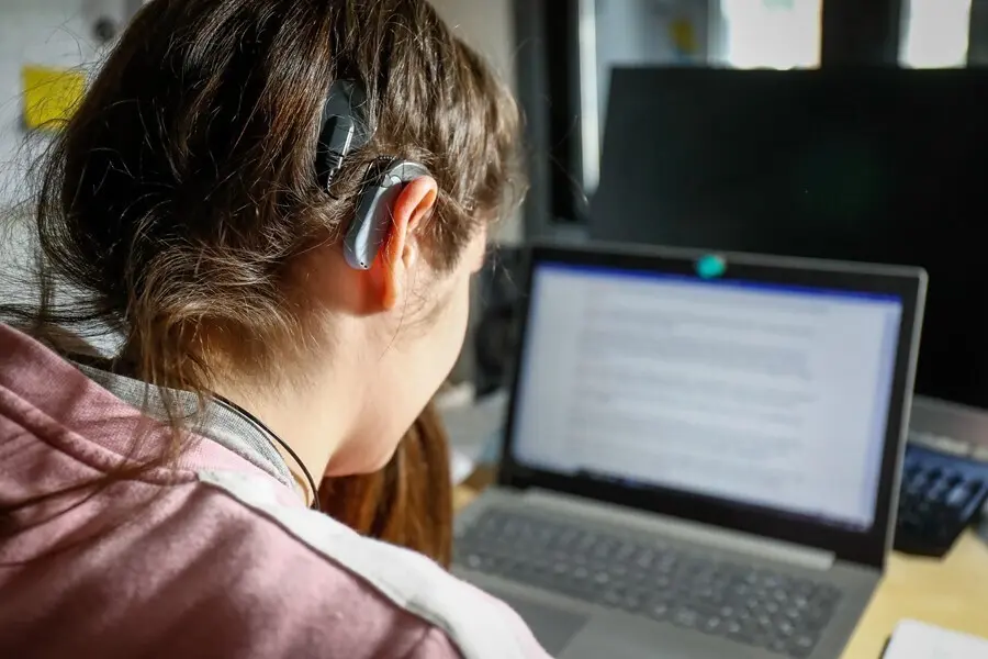 Archivo - Una joven usuaria de aud&iacute;fonos estudiando en su habitaci&oacute;n.