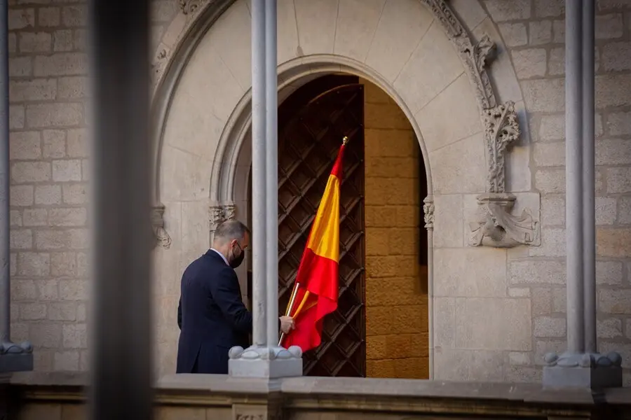 Un hombre retira la bandera de Espa&ntilde;a antes de que el president de la Generalitat comparezca en rueda de prensa en el Palau de la Generalitat