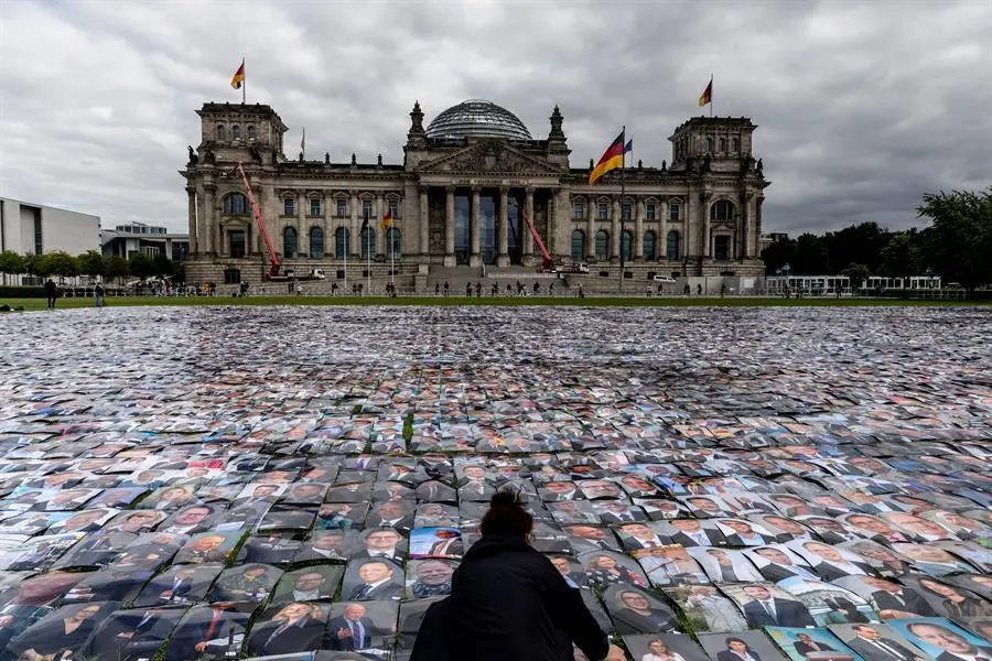 Un activista del grupo de derechos humanos Unverhandelbar (no negociable) coloca fotos de pol&iacute;ticos alemanes frente al edificio del Reichstag, sede del Parlamento alem&aacute;n, durante la protesta contra las violaciones de los derechos humanos en las fronteras exteriores de Europa en Berl&iacute;n, Alemania, el 16 de septiembre de 2021. (Protestas, Alemania) EFE/EPA/FILIP SINGER