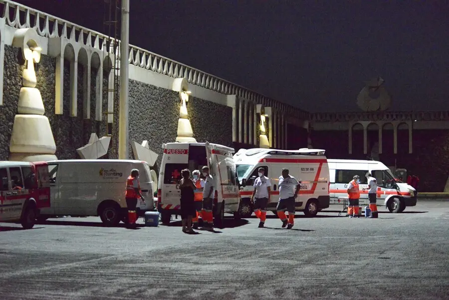 Veh&iacute;culos de Cruz Roja, atienden a varios migrantes a su llegada al muelle de La Restinga tras ser rescatados de una patera el pasado 23 de agosto