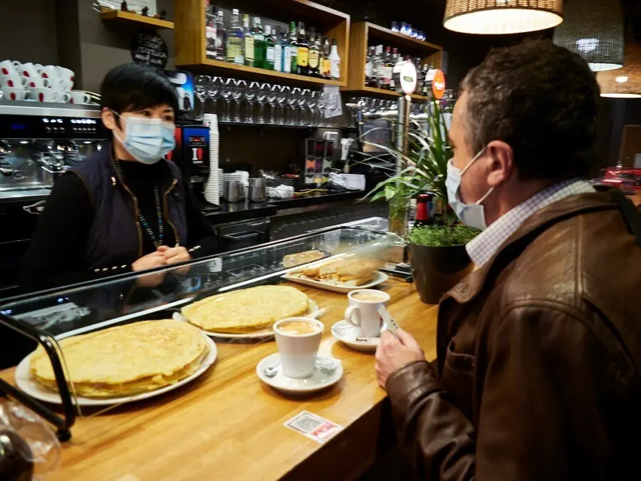 Archivo - Una camarera y un cliente en el interior de un bar