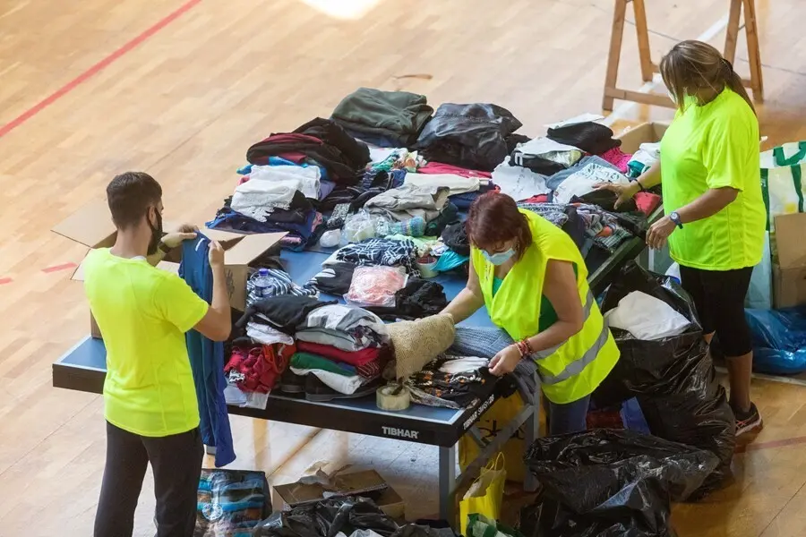 Varias personas colaboran y apilan ropa y objetos en el Polideportivo Severo Rodr&iacute;guez, donde se almacenan donaciones para los afectados por la erupci&oacute;n del volc&aacute;n de &lsquo;Cumbre Vieja