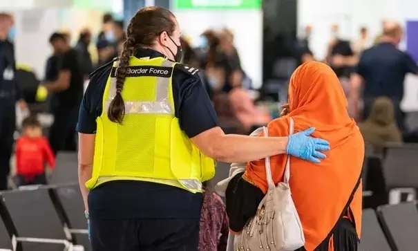 Un miembro de la Fuerza Fronteriza ayuda a una refugiada afgana a su llegada al aeropuerto de Heathrow en agosto. Fotograf&iacute;a: Dominic Lipinski / AFP / Getty Images