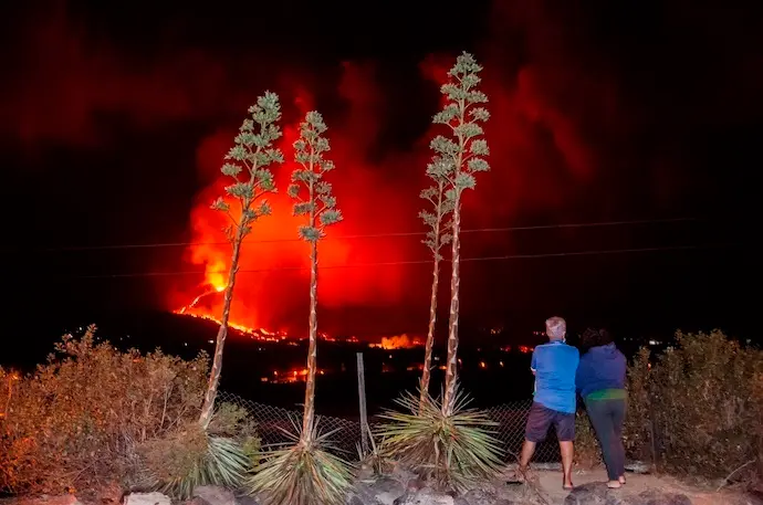 GRAF2426. LOS LLANOS DE ARIADNE (LA PALMA), 14/10/2021.- Una pareja vecinos de Los Llanos de Aridane observan como la colada se adentran en el barrio de La Laguna en la madrugada del jueves. El Plan de Emergencias Volc&aacute;nicas de Canarias (Pevolca) ha determinado una nueva evacuaci&oacute;n por la previsi&oacute;n de avance de la colada de lava del volc&aacute;n de Cumbre Vieja, en La Palma, que discurre m&aacute;s al noroeste y que afecta a entre 250 y 300 vecinos, informaron a Efe fuentes del Gobierno de Canarias. EFE/ Miguel Calero
