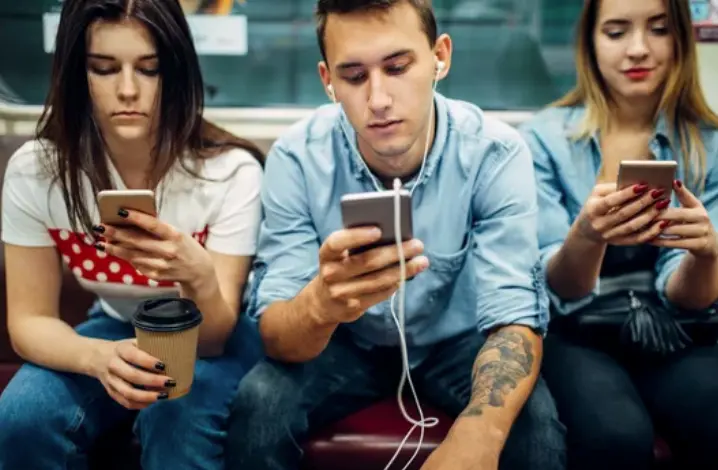 Varios j&oacute;venes con un tel&eacute;fono m&oacute;vil en la mano. / ALERTA