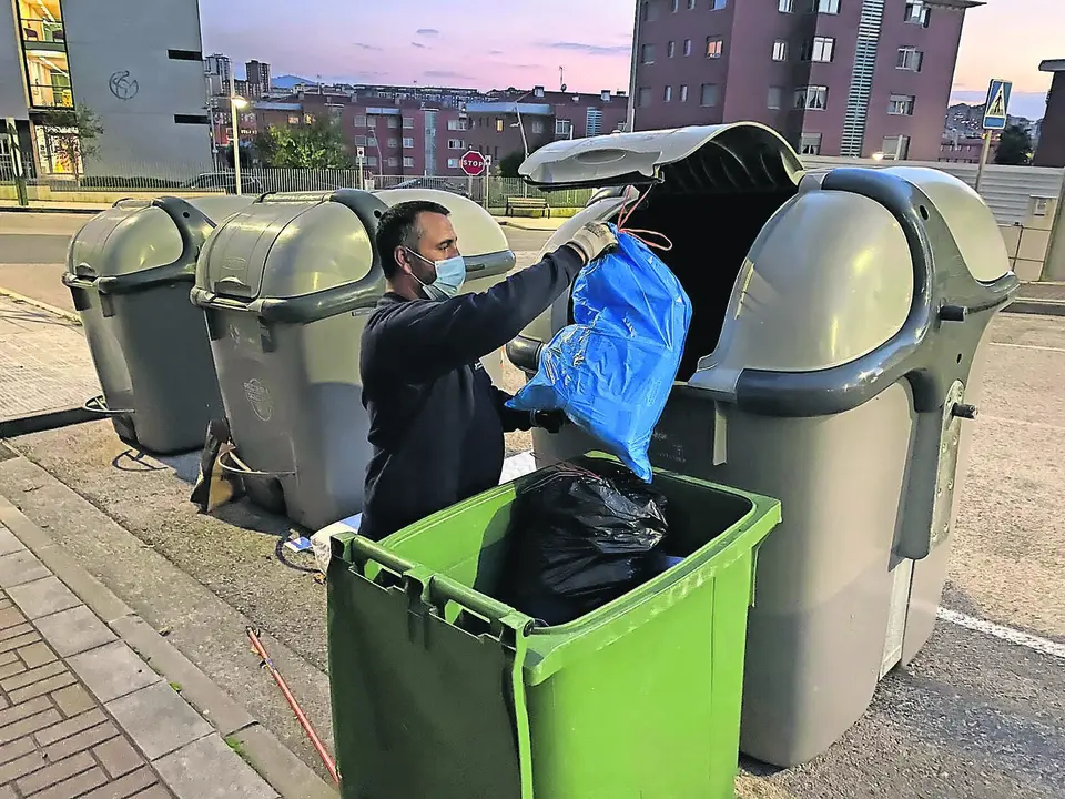 Una persona tira la basura en un d&iacute;a que cambia tras 28 a&ntilde;os el servicios de concesionaria en Santander. / HARDY